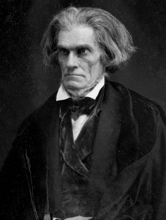 A historical black and white portrait of a man with long, wild, greying hair, a bad hair mistake.
