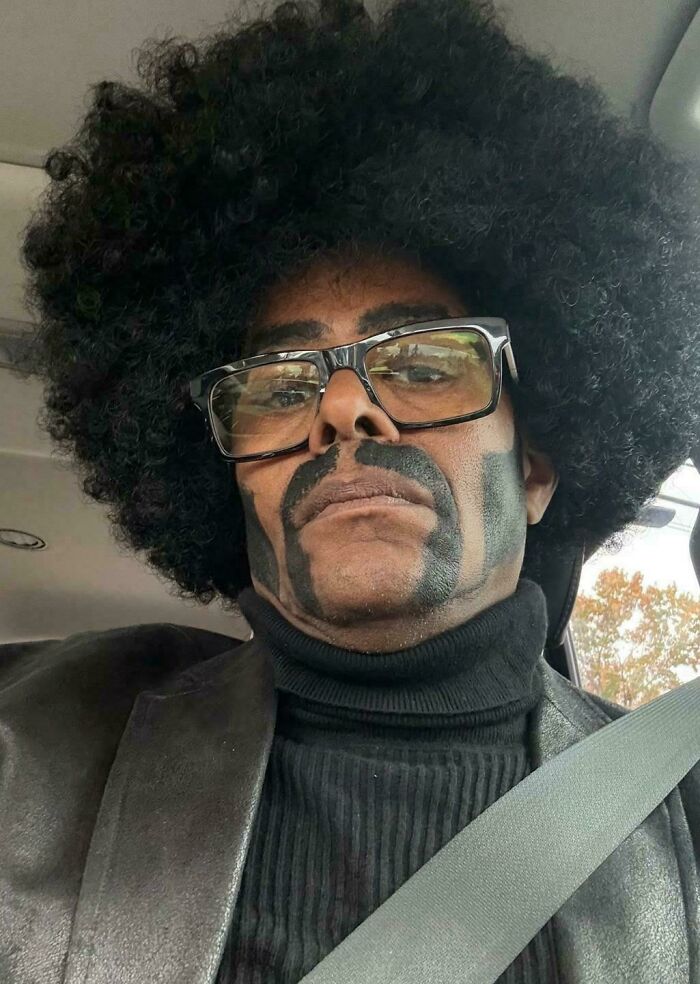 A man with a large afro wig and painted mustache, showcasing a bad hair mistake.