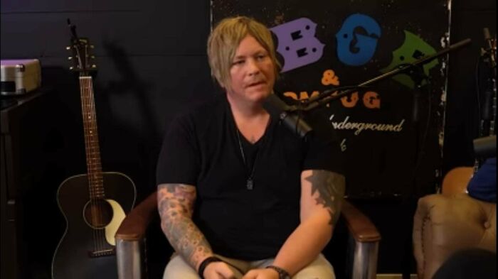 A man with shaggy blonde hair and tattoos, showcasing a bad hair mistake during an interview.