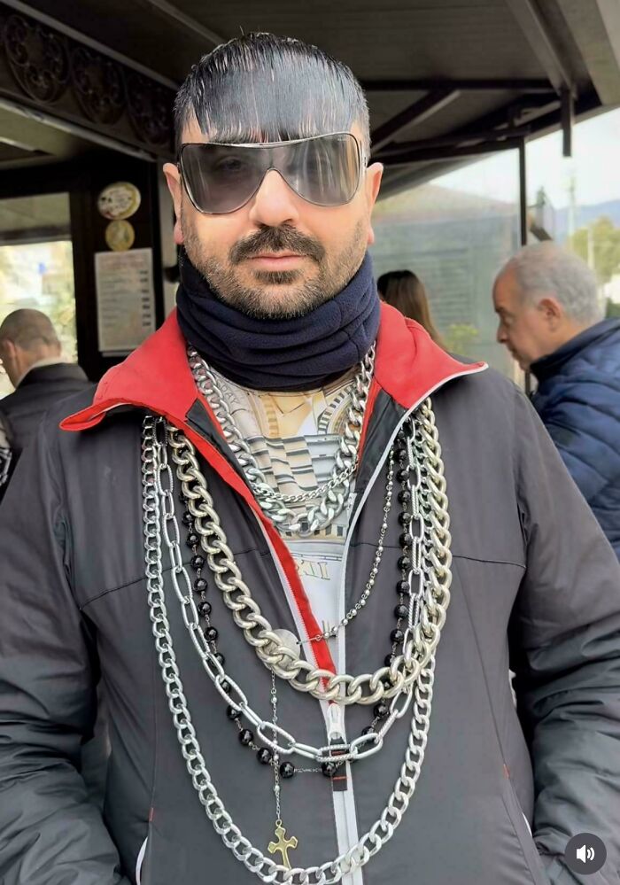 A man wearing multiple chains and sunglasses, with a noticeably bad hair mistake.