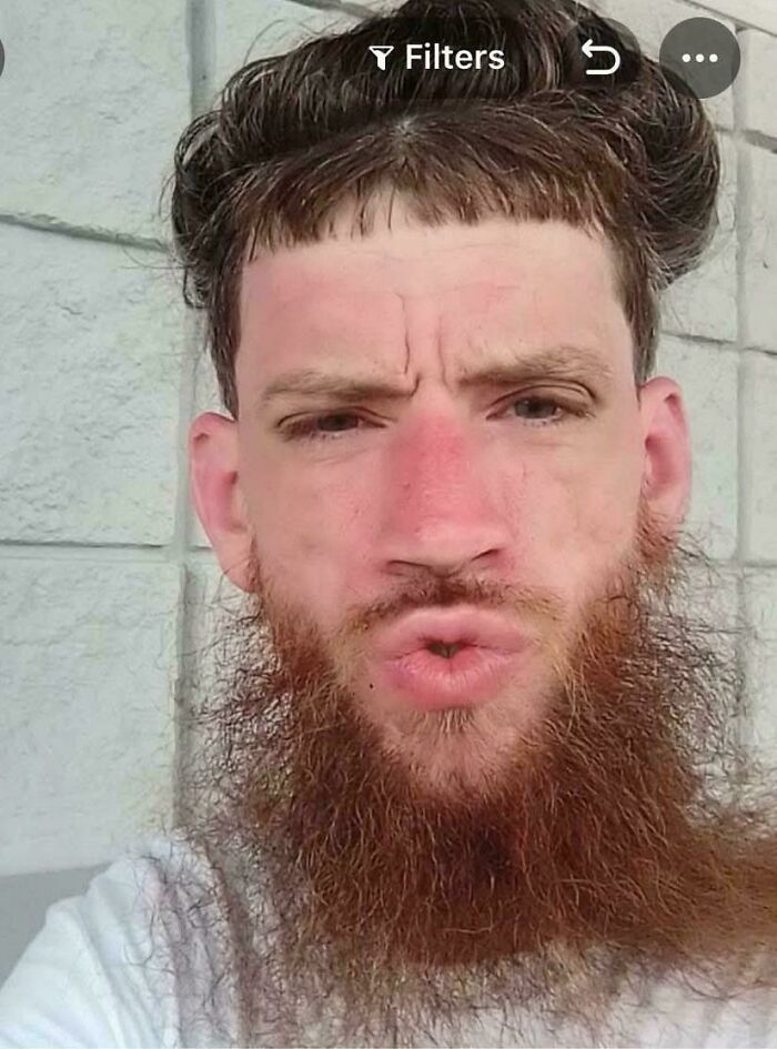 A man with a short, curly fringe and a long beard, an example of bad hair mistakes.