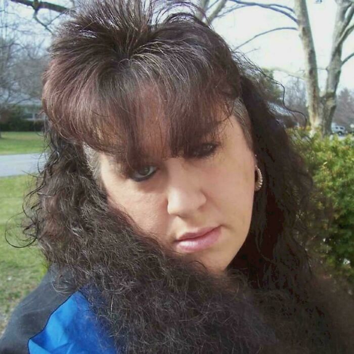 A woman with a hilariously bad hair mistake, featuring an extreme mullet and teased bangs.