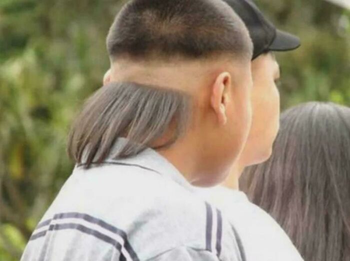 A close-up of the back of a person's head, showing a very short haircut with a long, thin patch of hair at the nape, a bad hair mistake.