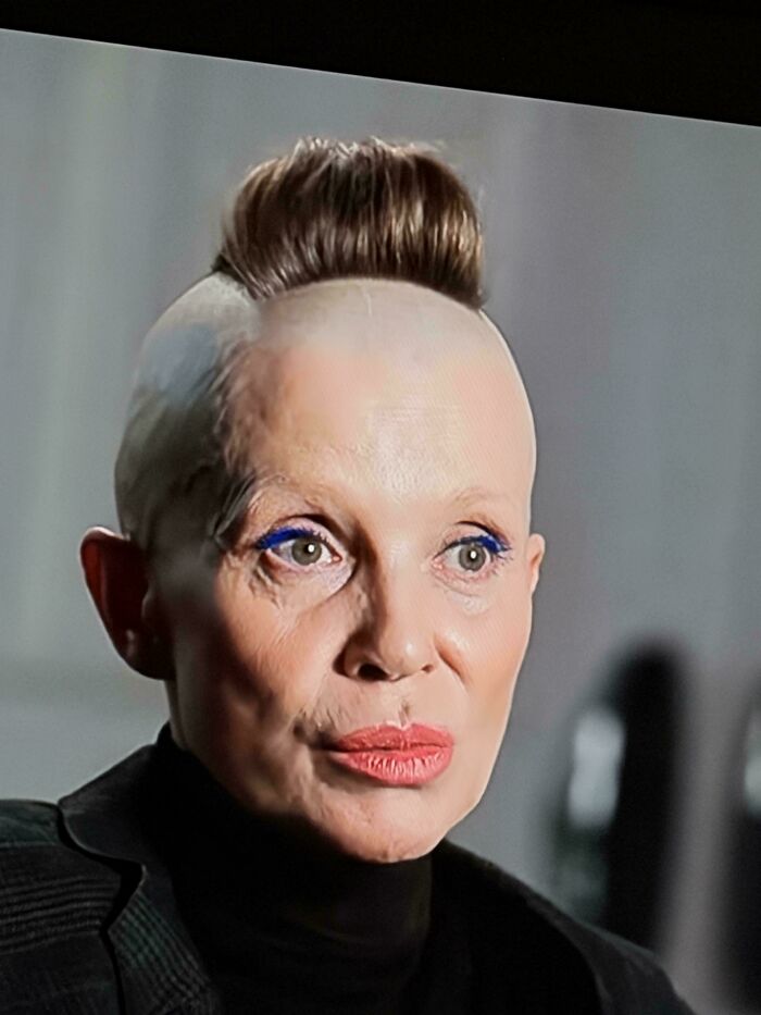 A woman with a dramatic mohawk hairstyle, a bald head, and vibrant blue eyeliner, showcasing a bad hair mistake.