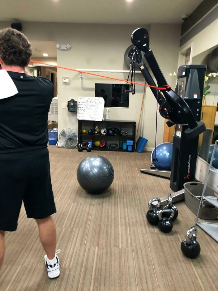 Man using resistance bands attached to a punching bag stand at the gym in a surprising fitness setup.