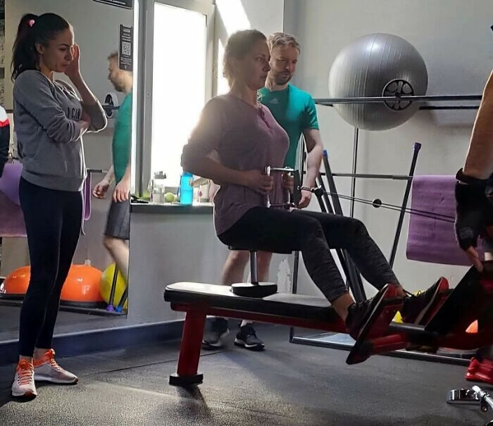 Woman exercising on gym machine while others watch, a potential Darwin Award contender moment at the gym.