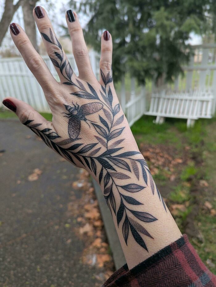 An intricate branch and insect tattoo stretching across a hand and wrist, showcasing stunning tattoos.
