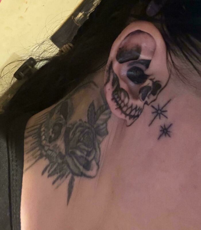 A stunning skull tattoo with roses on a shoulder and ear, showcasing unique tattoos.