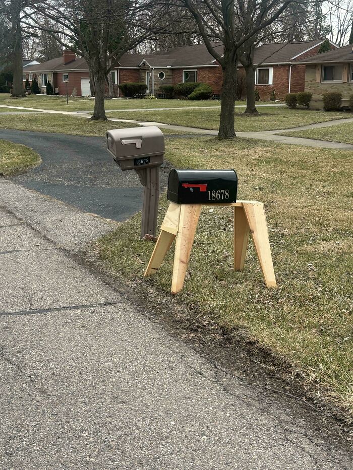 Black mailbox mounted on wooden sawhorse legs in a funny DIY project.
