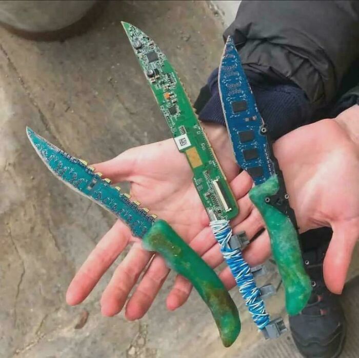 Three custom knives crafted from electronic circuit boards displayed in hands as questionable DIY projects.