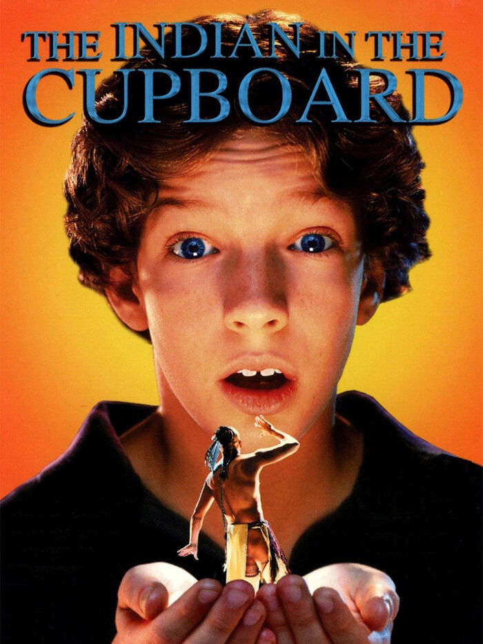 A 90s kid looking surprised with a small action figure in his hands, from The Indian in the Cupboard, a nostalgic meme.