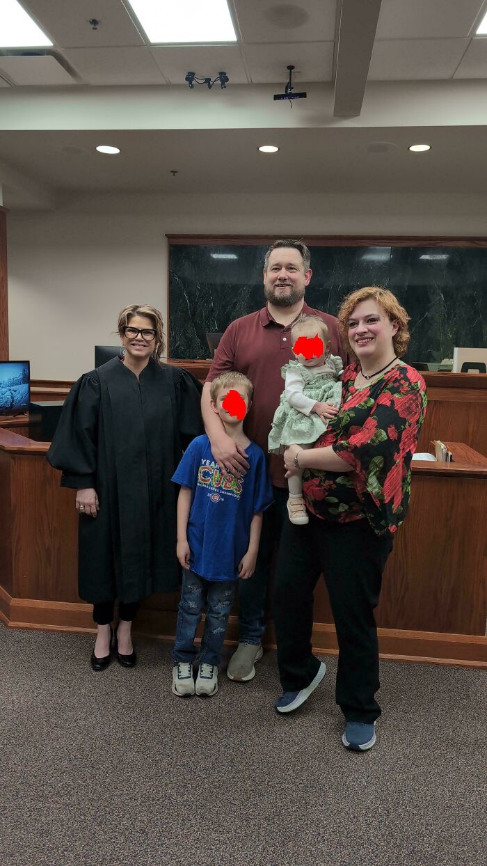 A smiling judge in a black robe with a family of a dad, mom, boy, and baby girl. This community is dedicated to dads.