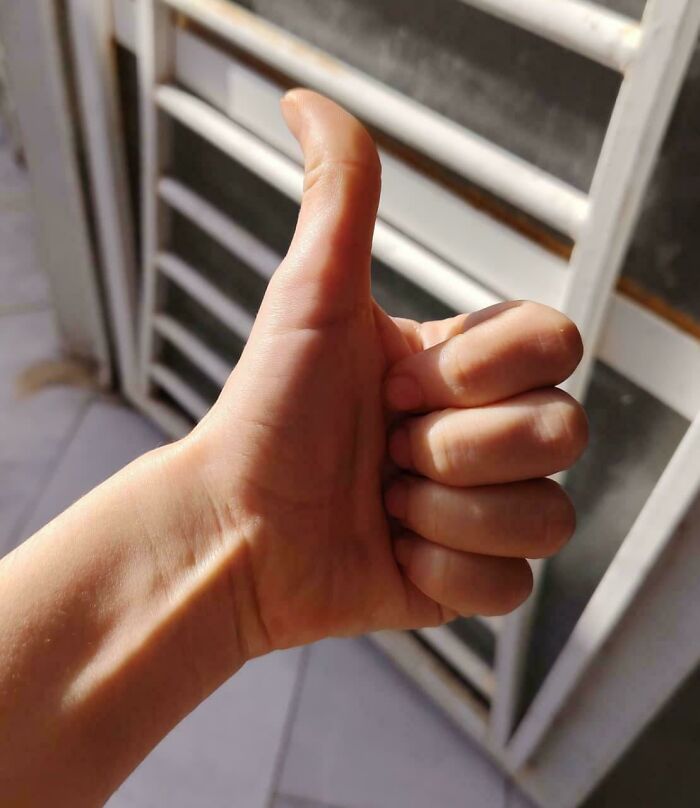 A hand giving a thumbs-up sign, showcasing a photo from the Not Interesting community.