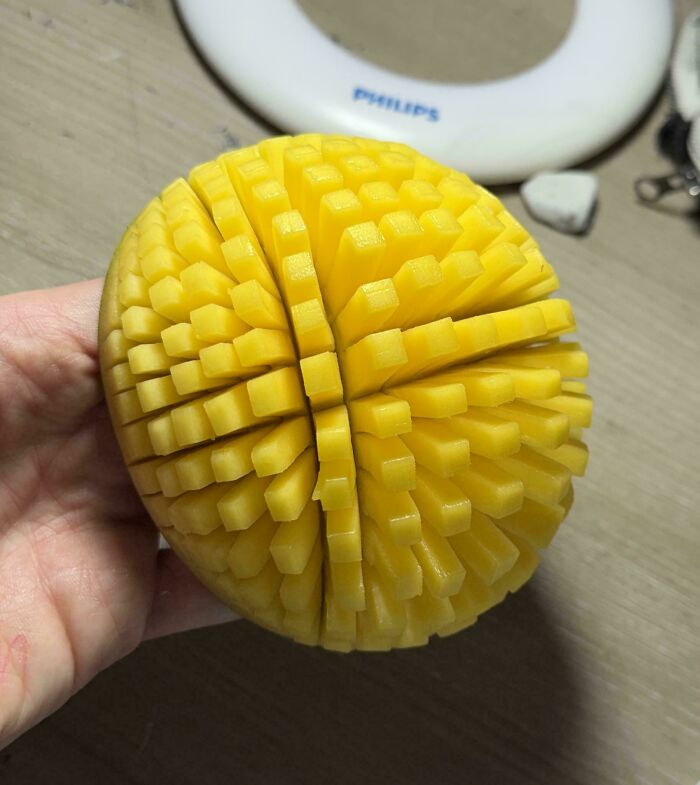 A hand holding a perfectly diced mango from the not interesting community, with the fruit looking like a porcupine.