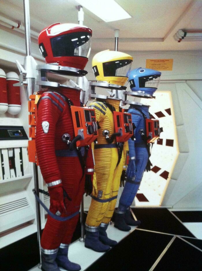 Retrofuturistic image showing three astronauts in red, yellow, and blue spacesuits, imagining the future.