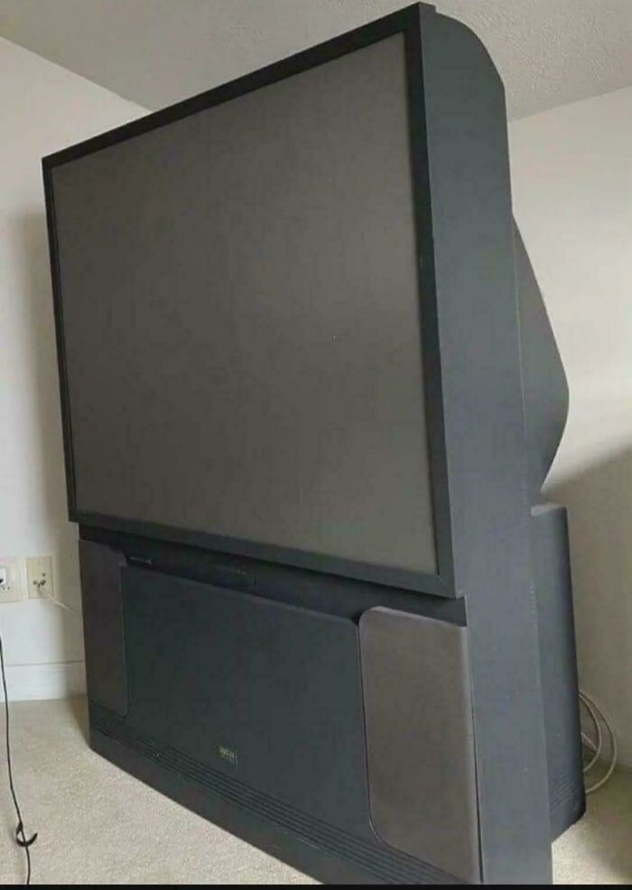 A large, old projection TV in a room, a historical photo of past technology.