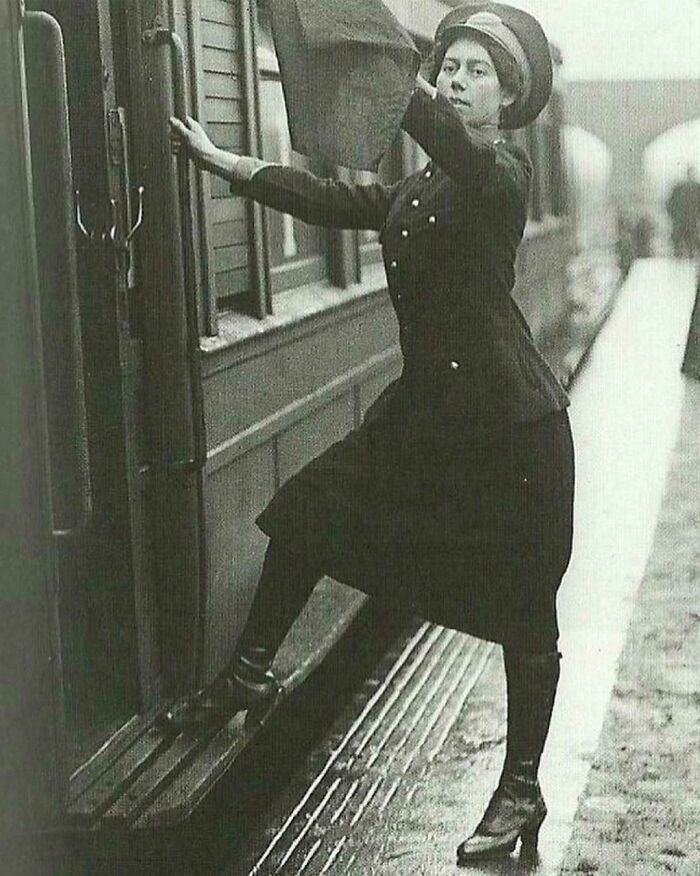 A historical photo of a woman in a uniform stepping onto a train, a glimpse into days we will never experience again.