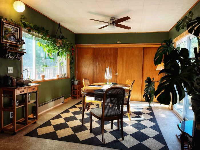 A cozy dining area featuring a wooden table, checkered rug, and lush green plants, showcasing great home decor projects.