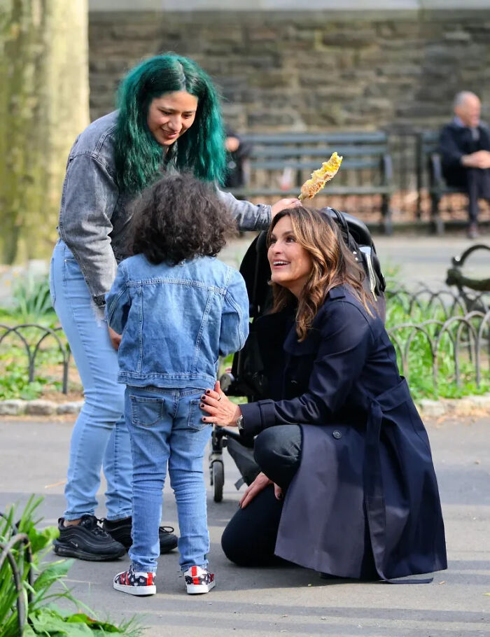 Mariska Hargitay kneeling and talking to a child in a park. Fascinating pics & quick facts for a brain boost.