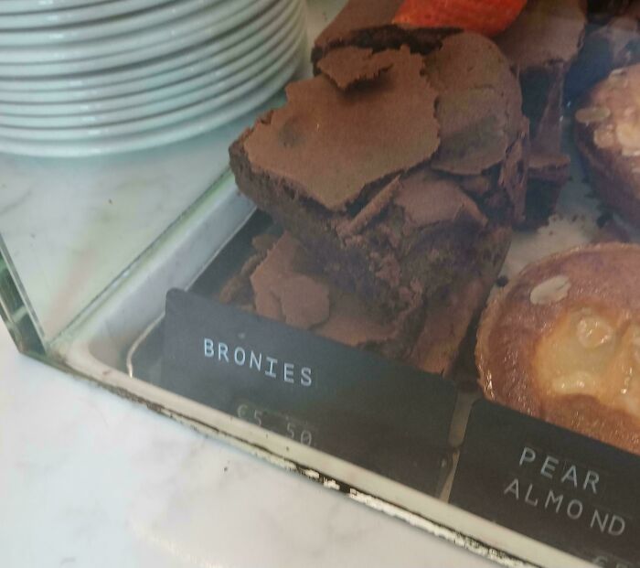 A baffling image of chocolate brownies in a display case with a misspelled sign that reads Bronies.
