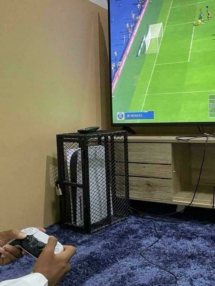 A PlayStation 5 console is locked inside a peculiar metal cage next to a TV. People spotted this peculiar thing in real life.