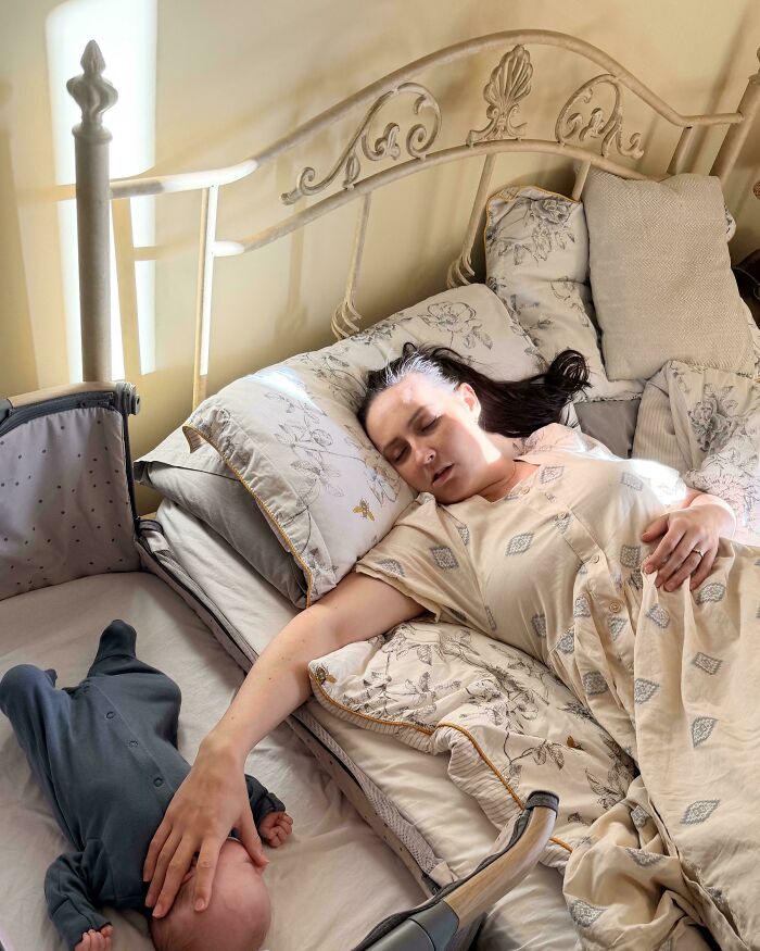 A tired mother reaches out to touch her baby’s head while resting, capturing an Accidental Renaissance moment.