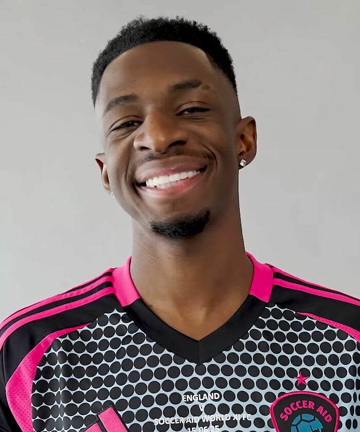 TBJZL smiling in a Soccer Aid jersey with a gray background, highlighting his bio and career highlights.