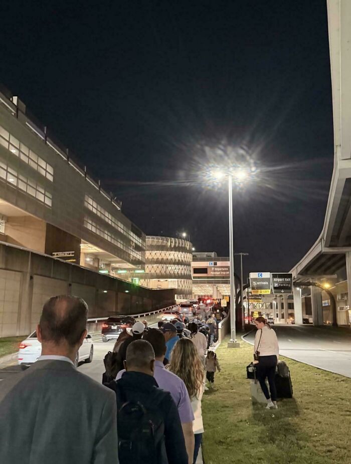 People waiting in a long line outside an airport at night, illustrating challenges of life in America travel.