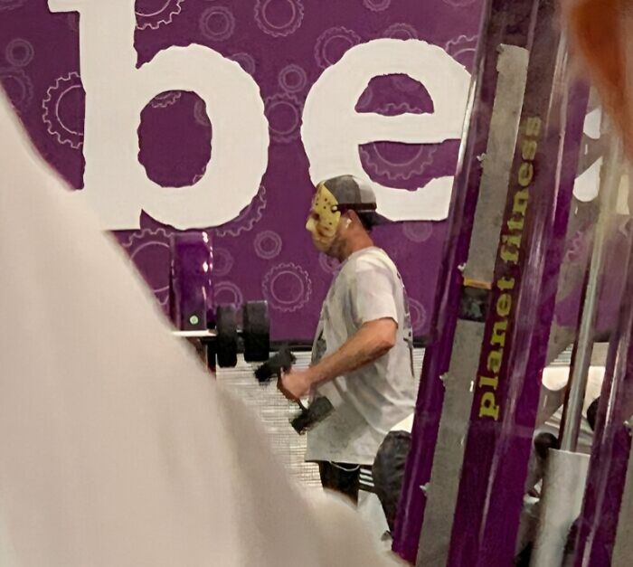 Man wearing a hockey mask lifting dumbbells at Planet Fitness gym, a surprising gym moment captured.