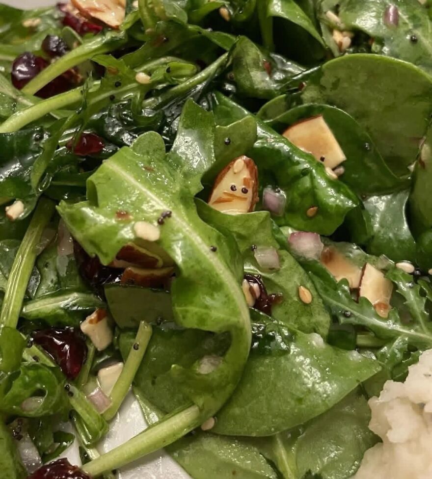 Close-up of a spinach salad showing an almond piece resembling a face, an example of pareidolia in food.