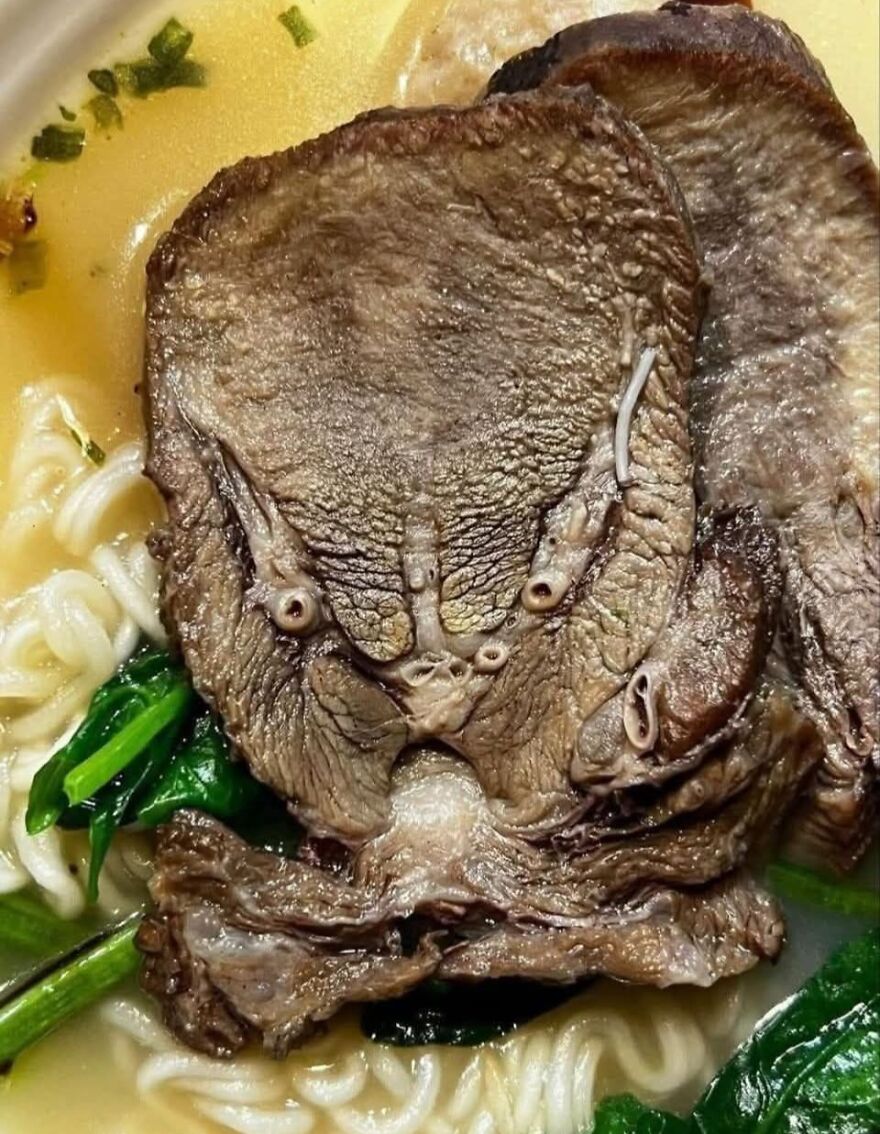 Close-up of a mushroom in ramen noodles resembling a face, illustrating pareidolia in food photography.