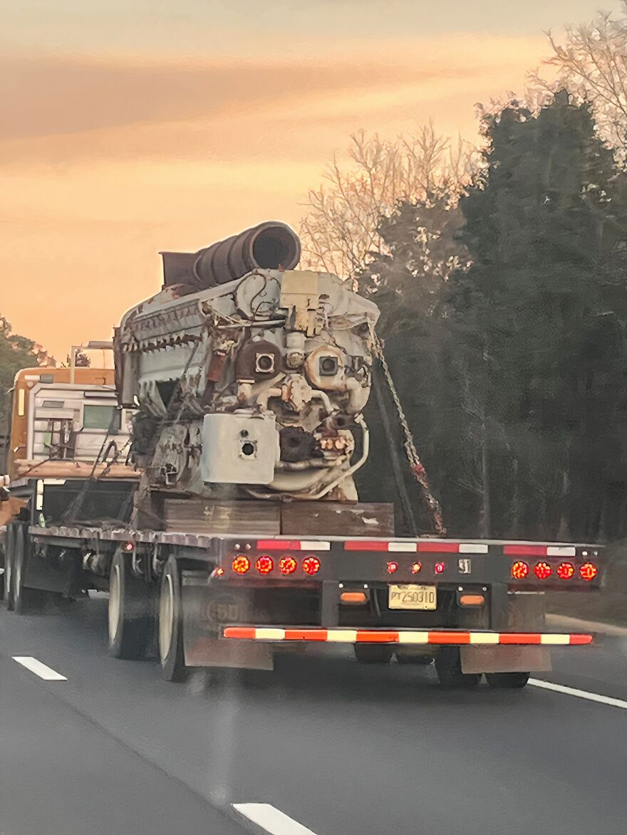 Large engine on flatbed truck resembling a face, an example of pareidolia captured on a highway during sunset.