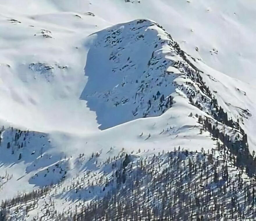 Snow-covered mountain casting a shadow that resembles a human face, illustrating a striking pareidolia example.