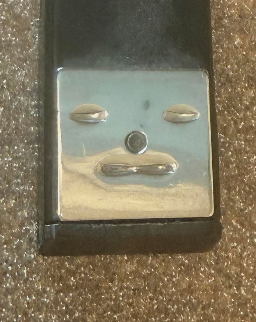 A metal switch on a textured surface resembling a face, an example of pareidolia captured in an everyday object.