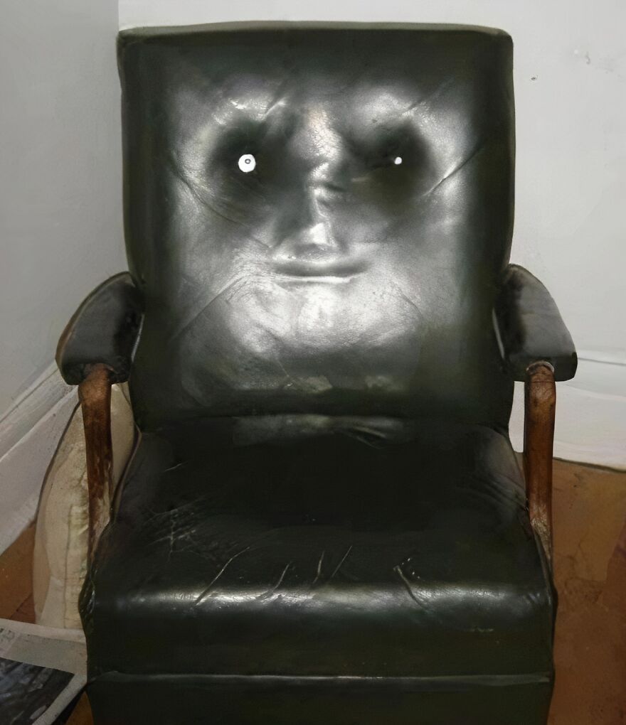Worn leather chair with creases and reflections creating a pareidolia effect resembling a smiling face.