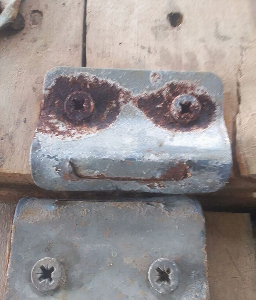 Rusty screws and metal parts on wood resembling a face, an example of pareidolia captured in an everyday object.
