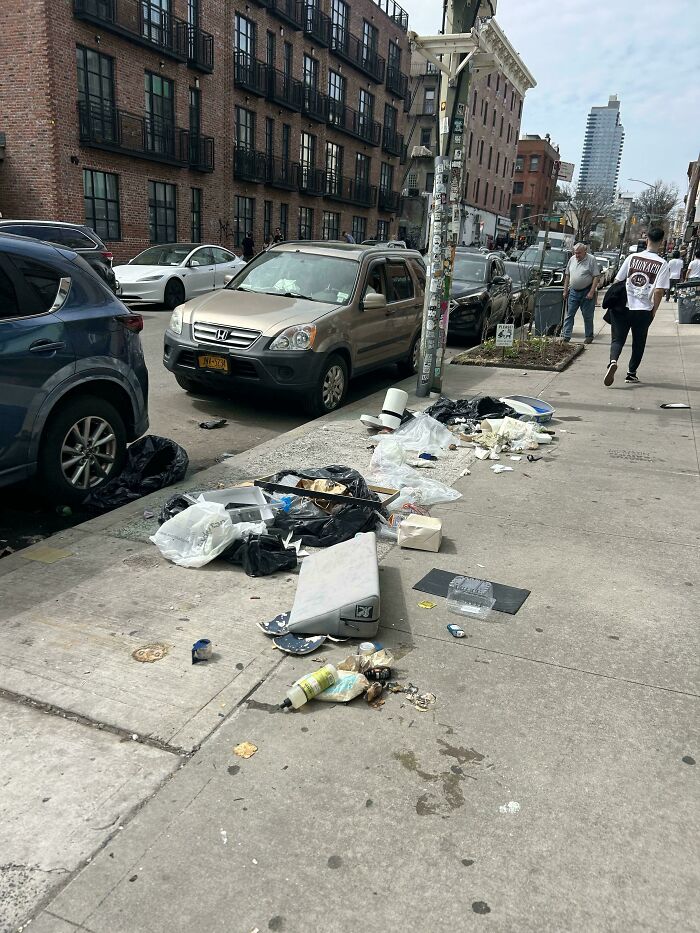 Urban hell street littered with trash and debris beside parked vehicles