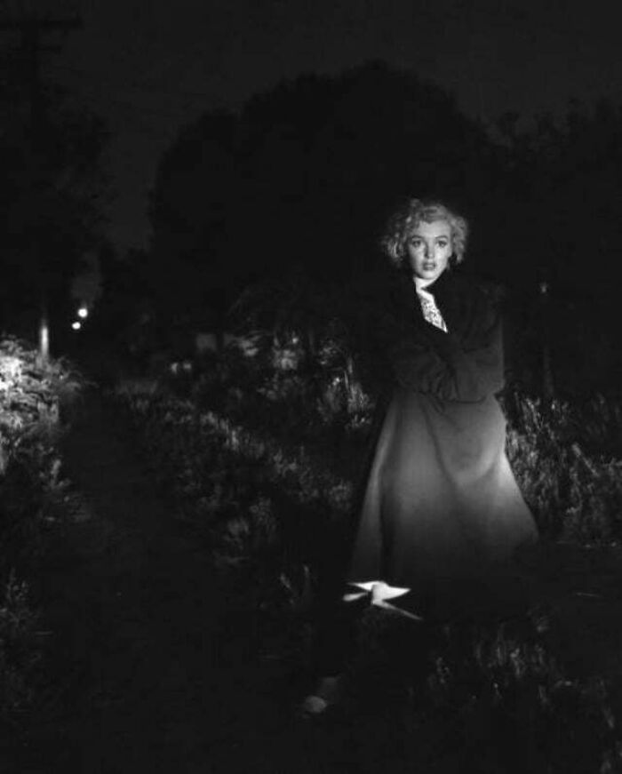 Black and white historic photo of a woman standing outdoors at night, capturing a rare moment from a different era.
