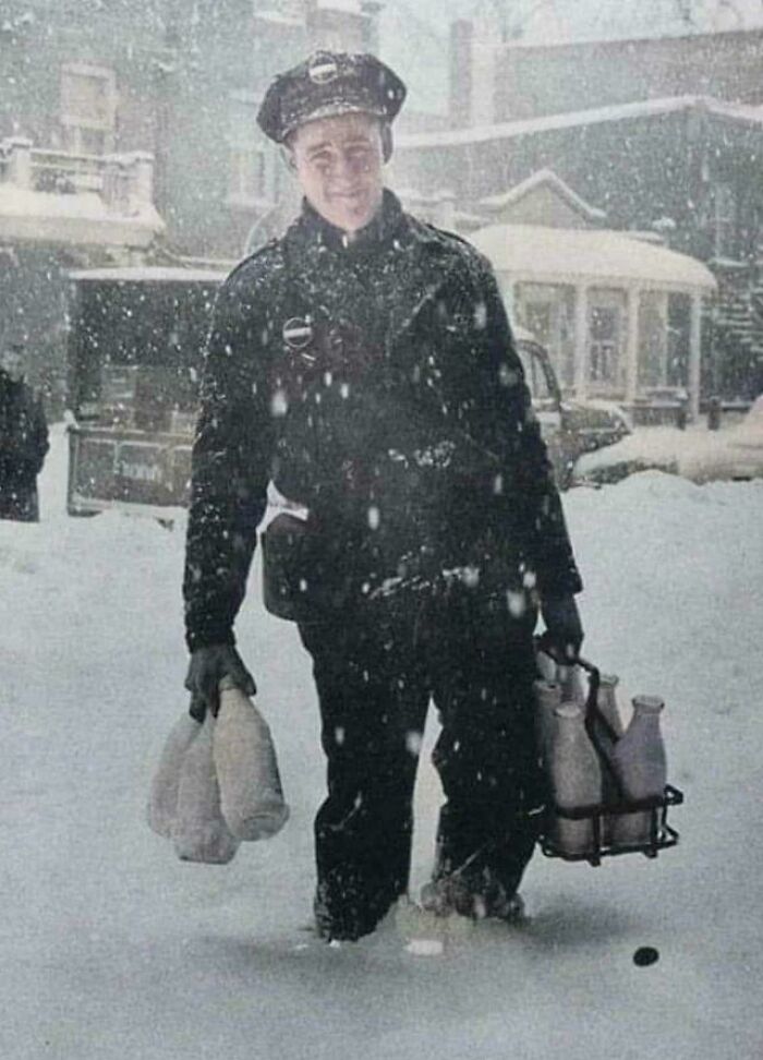 Historic photo of a milkman delivering bottles in heavy snow, showcasing life in a different era.