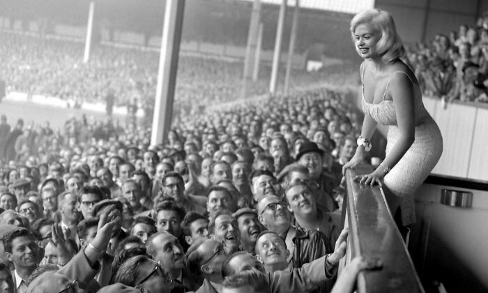 Vintage crowd eagerly reaching toward a woman at a stadium, showcasing rare and fascinating historic photos of a different era.