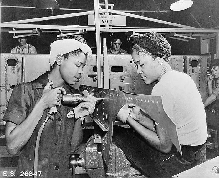 Two women working with metal in a factory showcasing rare and fascinating historic photos of life in a different era.