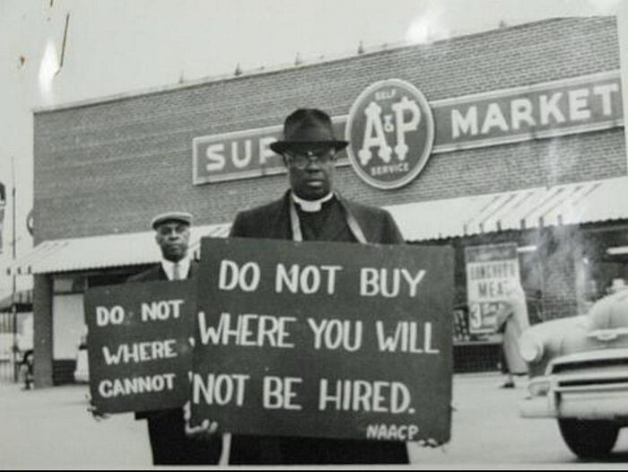 Historic photo of men protesting outside a supermarket holding signs during a civil rights boycott in a different era.