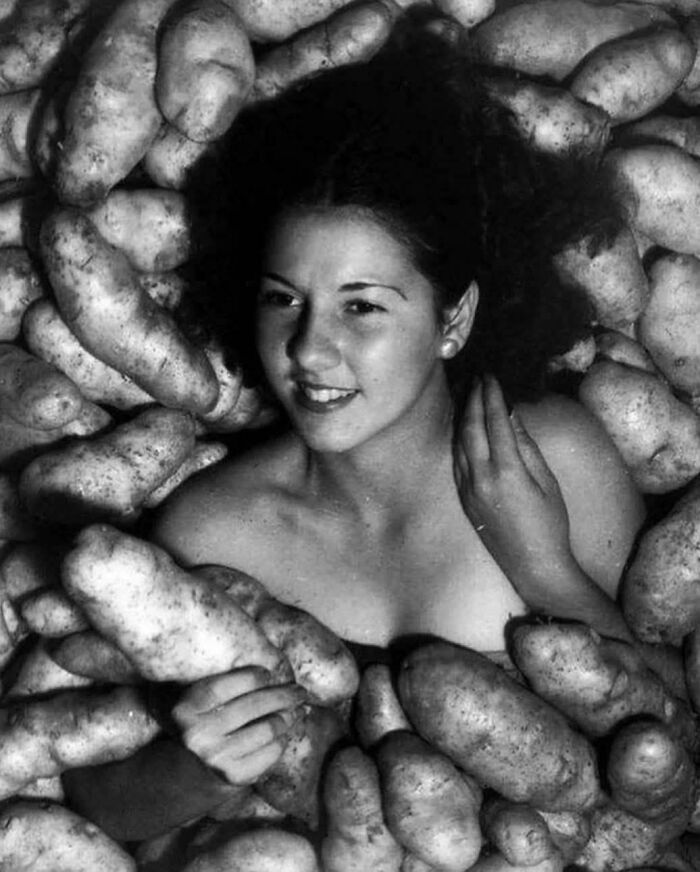 Young woman surrounded by potatoes in a rare and fascinating historic photo capturing life in a different era.
