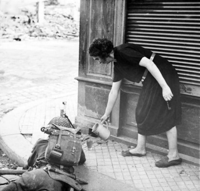 Woman pouring water for a wounded soldier in a rare historic photo capturing life in a different era.