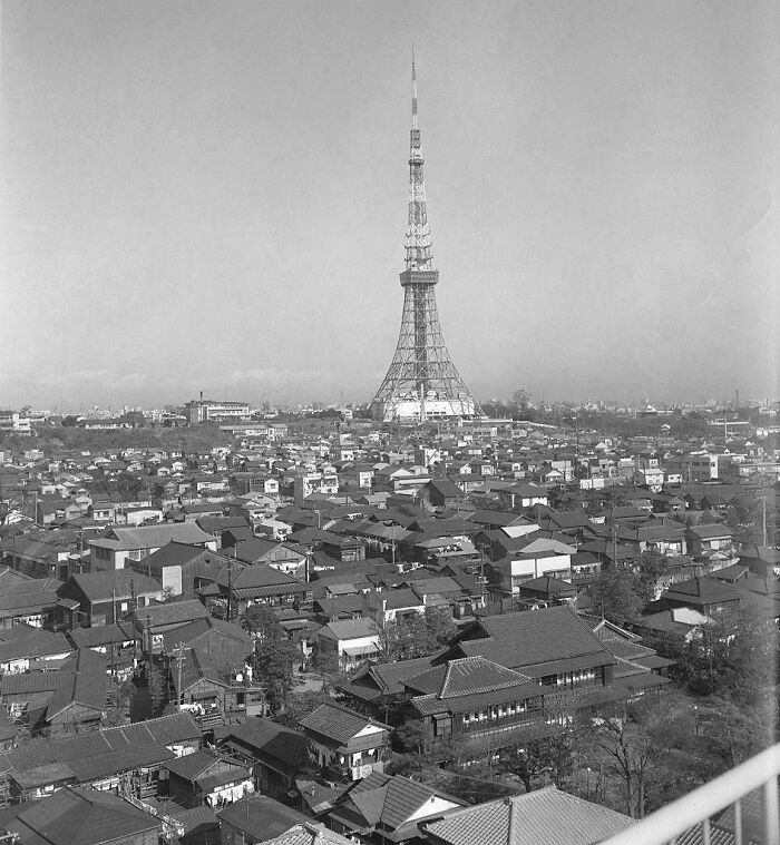 Historic black and white photo showing a cityscape with a tall communication tower, illustrating life in a different era.