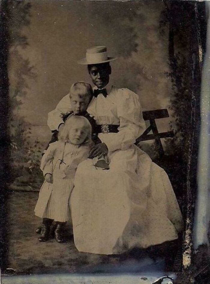 Historic photo of a woman and two children dressed in vintage clothing, illustrating life in a different era.
