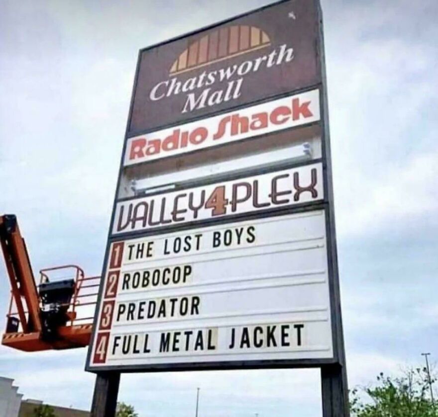 Retro shopping mall sign featuring Radio Shack and a Valley 4 Plex movie listing popular 80s films.