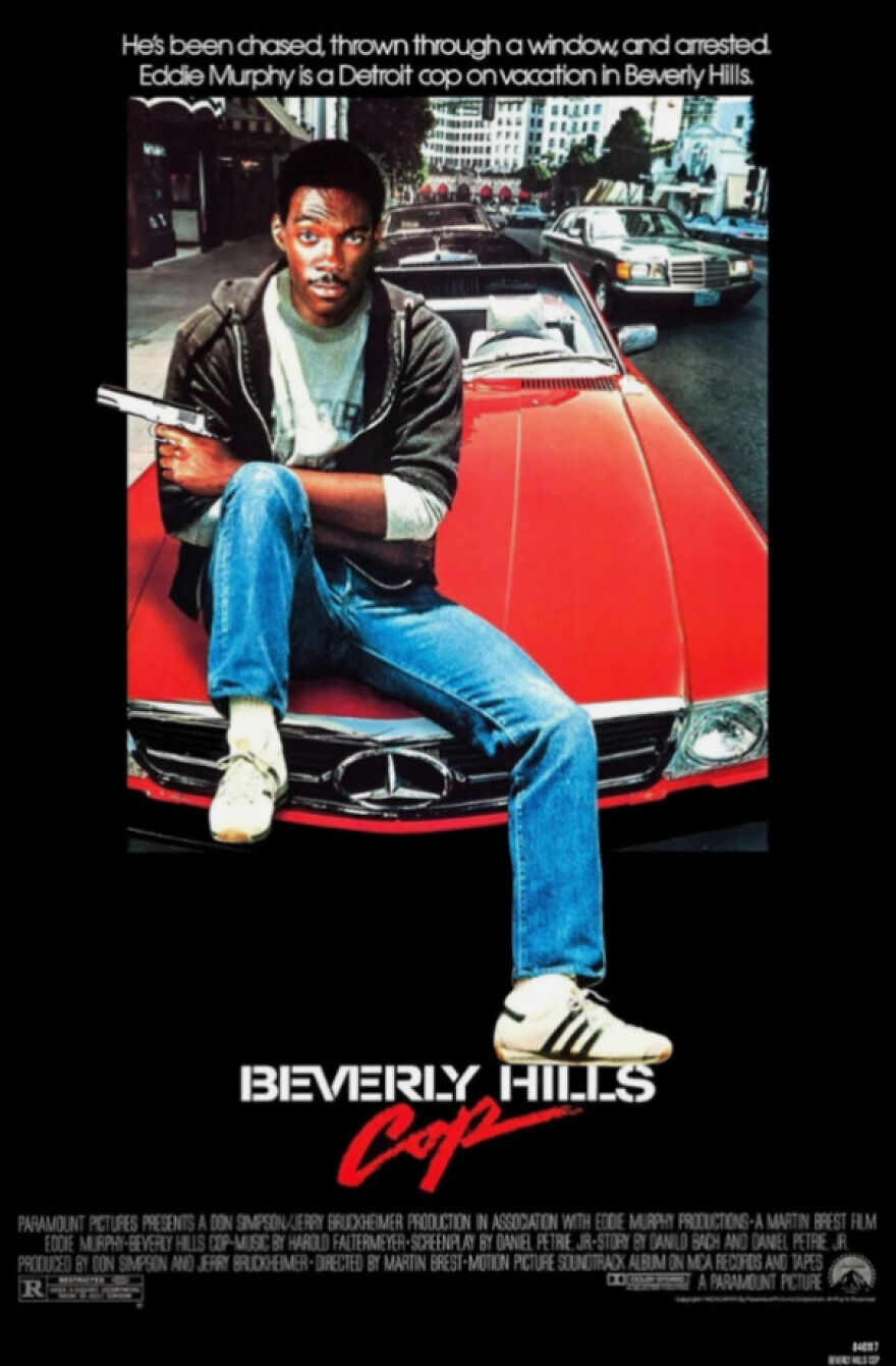 Eddie Murphy in an iconic 80s cop movie poster sitting on a red convertible Mercedes, showcasing 80s life and style.