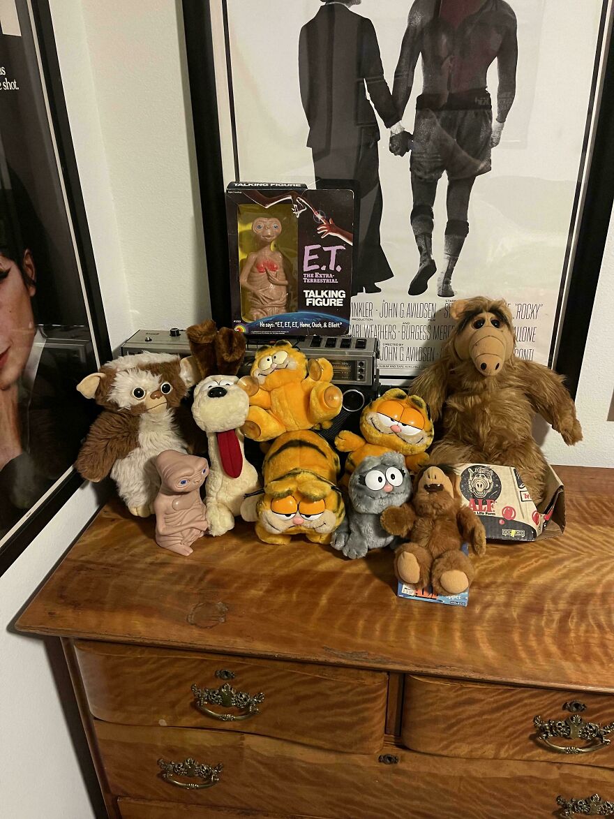 Collection of 80s nostalgic toys including E.T., Alf, Garfield, and other characters on a wooden dresser showing parts of our lives.