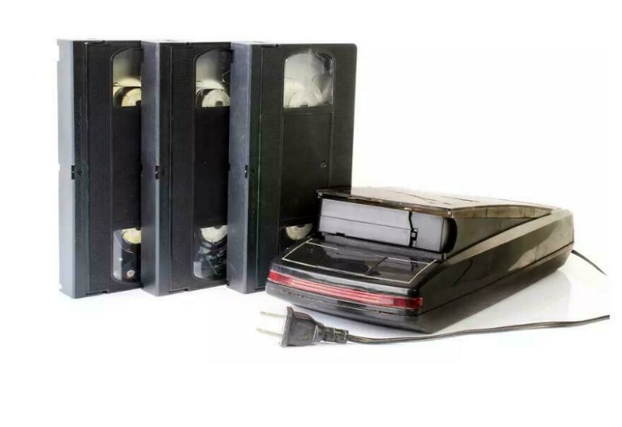 Black vintage VHS player with three VHS tapes, representing 80s technology that no longer exists.